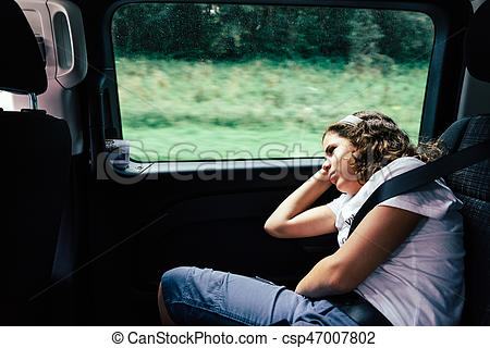 Teenager sleeping in the backseat of a car on a trip.