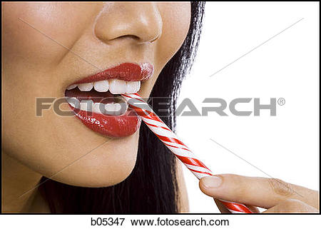 Picture of Closeup of woman with red lipstick eating candy cane.