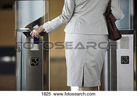 Stock Image of Businesswoman swiping card in entrance barrier.