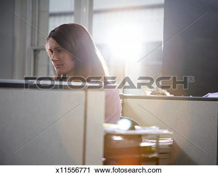 Stock Photography of Woman sitting at desk in office (lens flare.