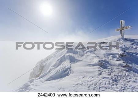 Stock Photography of Summit cross covered with snow on mountain.