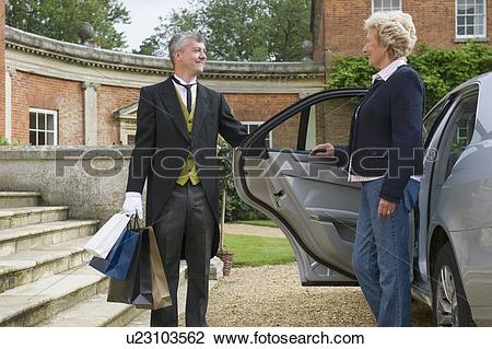 Stock Photo of Butler opening car door for older woman u23103562.
