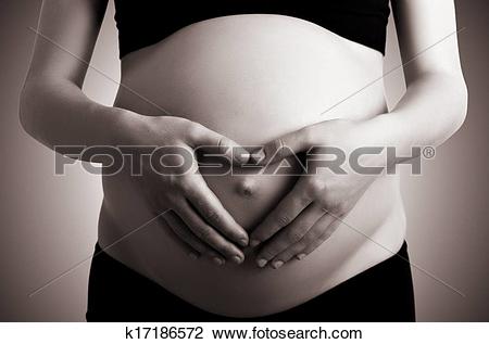 Stock Photo of hands in heart shape on belly of pregnant woman.