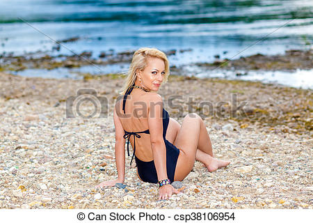 Stock Images of girl in a black bikini swimsuit on the stony beach.
