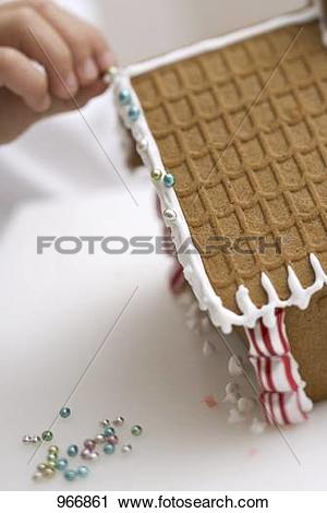 Stock Photography of Child decorating gingerbread house with sugar.