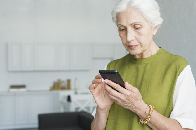 Portrait of senior woman texting on cell phone at home Photo.